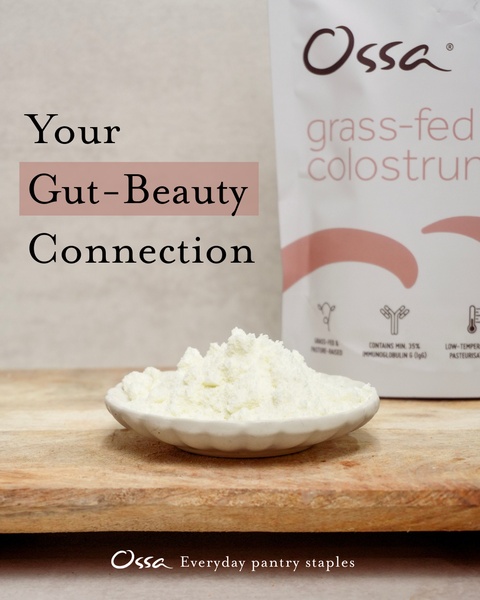A clean, minimalist product spotlight showcasing grass-fed colostrum powder on a wooden board, highlighting the link between gut health and skin appearance.